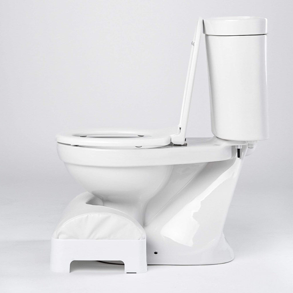 Side view of a LUXE Footstool in tucked in front of a toilet.