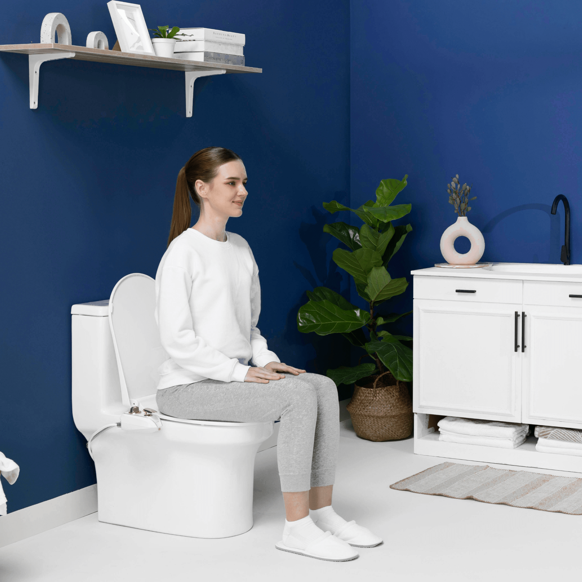 NEO 320 Plus Rose Gold installed, with a person sitting on the toilet, in a modern blue bathroom