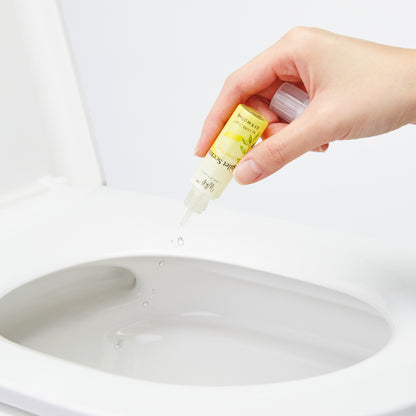 Hand squeezing drops of Lemon Peel Whift Drops into the toilet