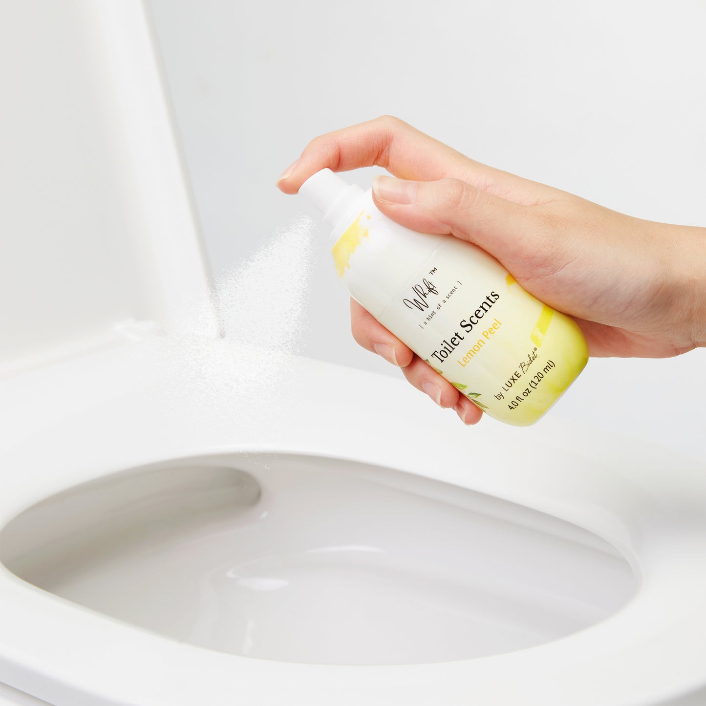 Hand spraying Lemon Peel Whift into the toilet