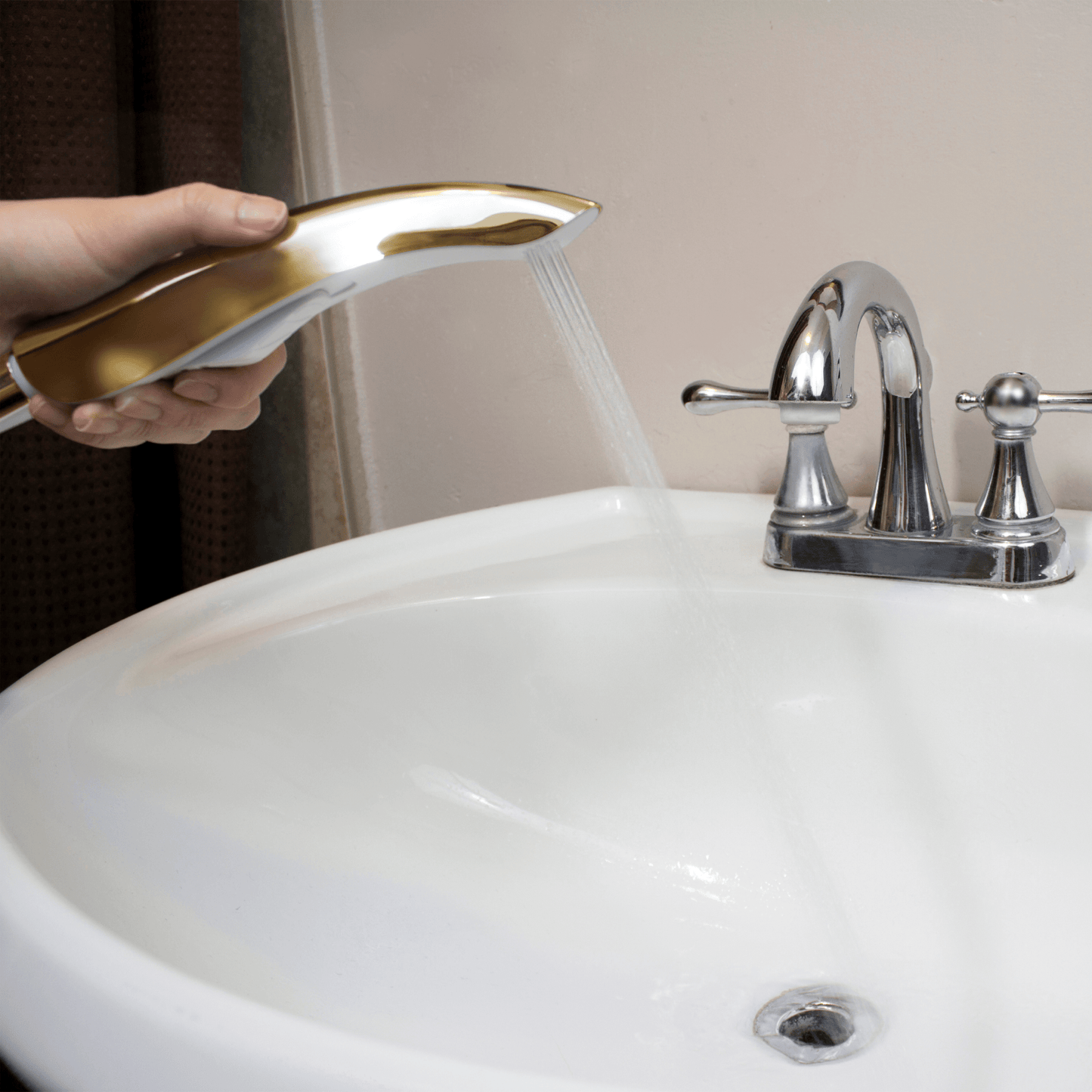 Handheld Bidet NEO 70 (Gold) spraying a stream of water into sink