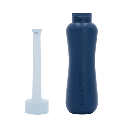 The baby blue nozzle cap is extended out and separated from the navy blue bottle of the LUXE Portable Bidet