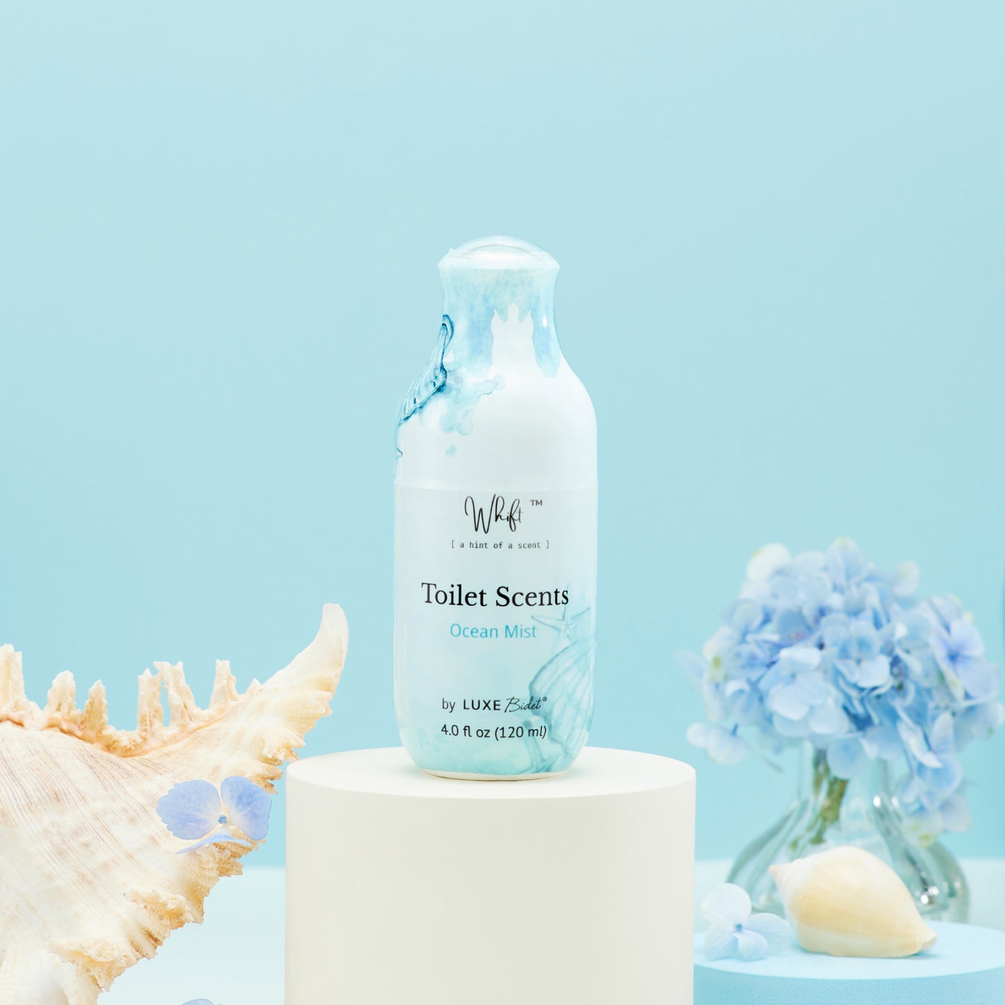 120 mL Ocean Mist Whift Toilet Scents Spray on a platform with flowers and shells around it