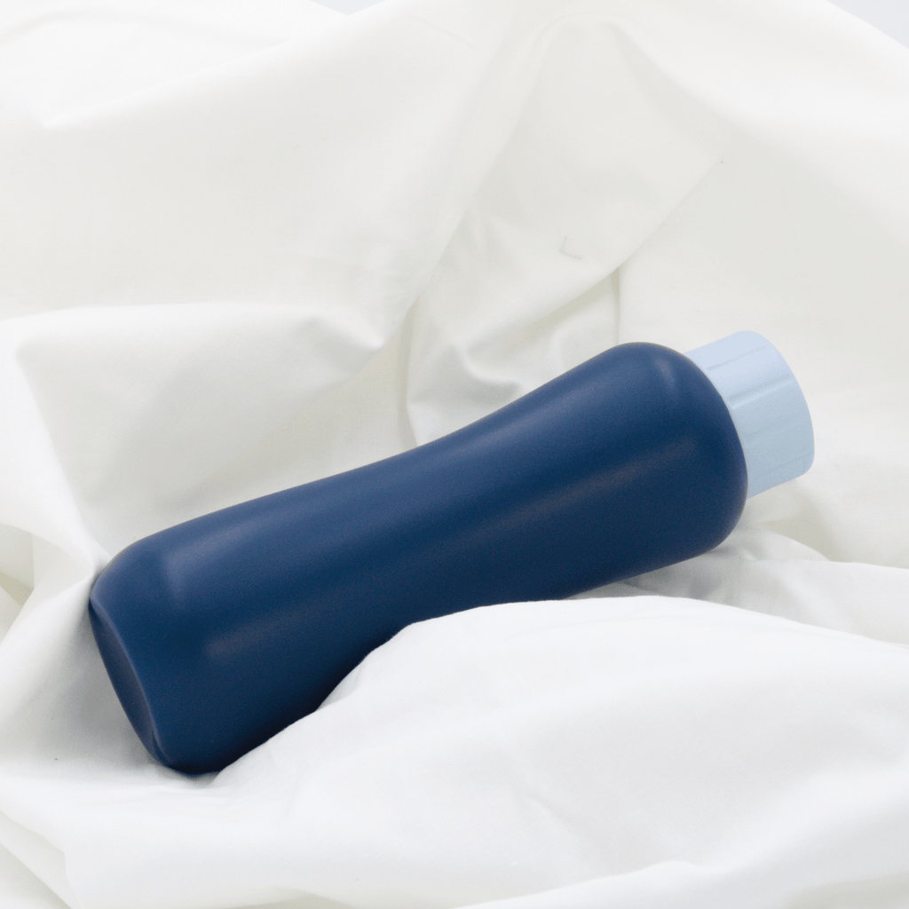 LUXE Portable Bidet is a navy blue bottle with a baby blue cap. The bidet is on a white sheet
