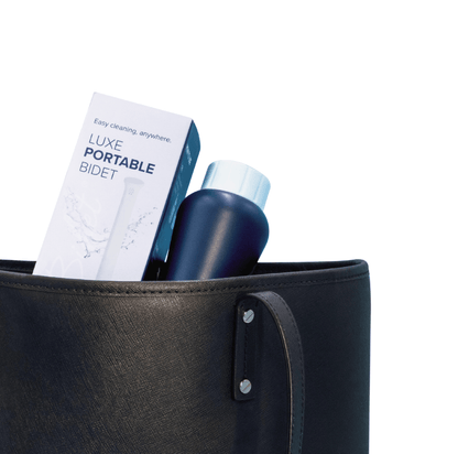 LUXE Portable Bidet is in a purse with its packaging box, slightly extending out of the top