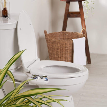 LUXE Comfort Fit Toilet Seat installed on a toilet in a modern-styled bathroom with plants, a basket with towels, and a stool